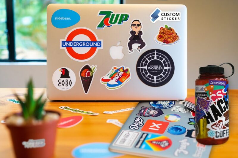 A Laptop and Water Bottle Covered in A Variety of Custom Stickers