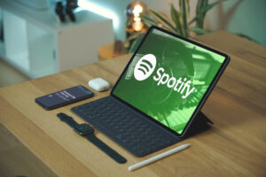 Laptop on a wooden table with Spotify background on desktop