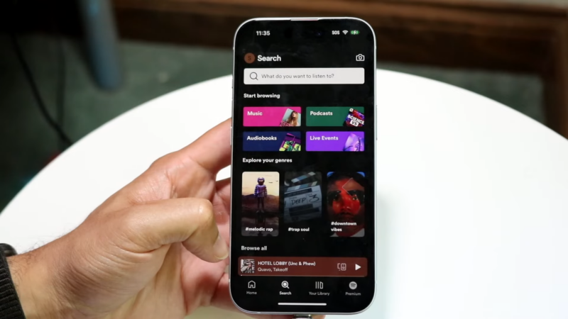 A Person Holding an iPhone with The Spotify App Open on The Search Tab