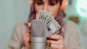 A Podcaster Holding Money in Front of A Microphone, Symbolizing Securing Sponsorships for Your Podcast