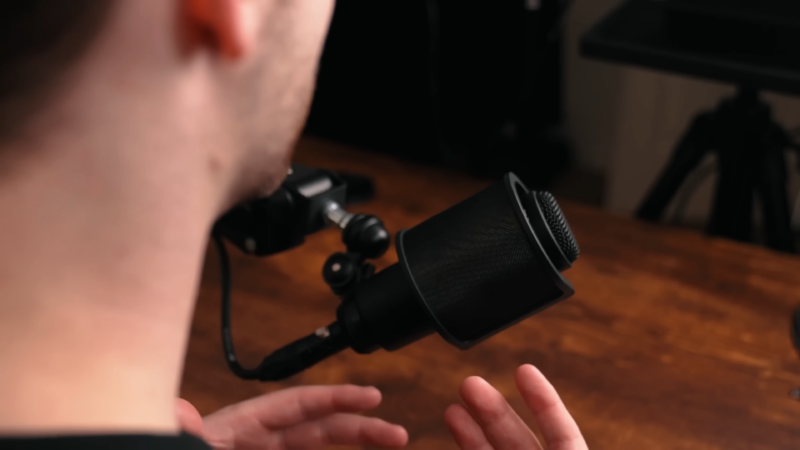 A Close-Up of A Microphone with A Person's Hands Gesturing