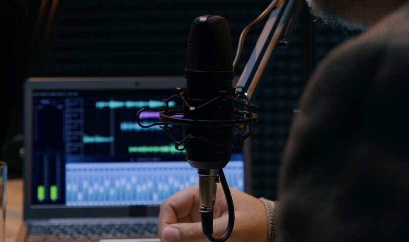 Close-up view of a microphone and laptop screen displaying audio waveforms