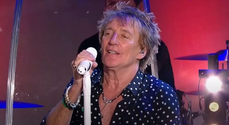 Rod Stewart, in a polka-dot shirt, sings with intensity