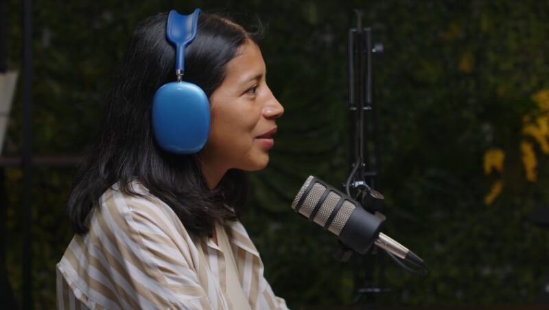 A woman speaks into a microphone, her voice echoing in a quiet studio