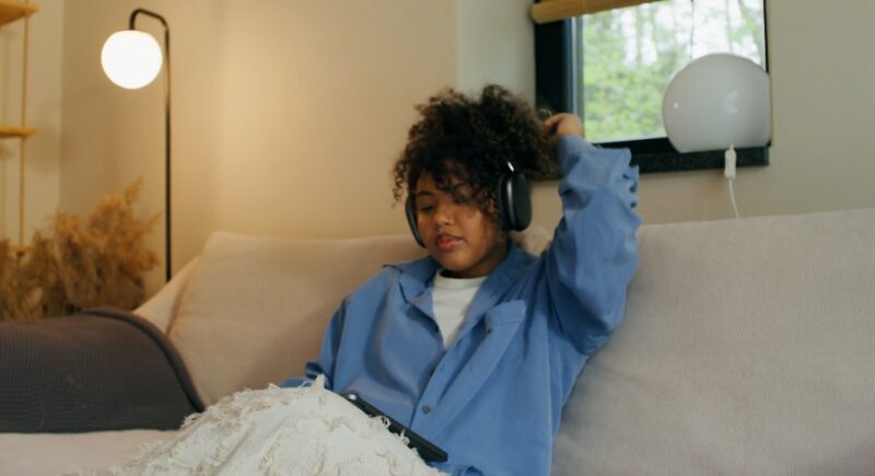Young woman engrossed in music, wearing headphones and a light blue button-down shirt