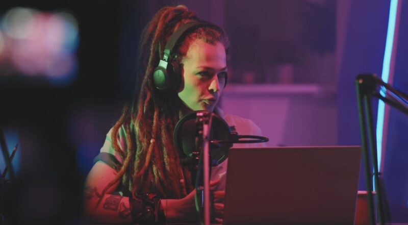 Focused and vibrant, a woman with dreadlocks immersed in a recording session