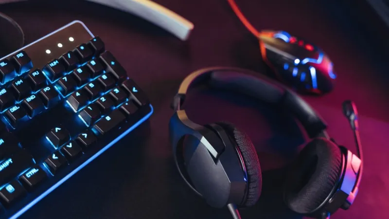 A gaming headset, mouse, and keyboard rest on a streamerโs desk