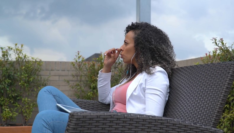 A woman in a white blazer, listening to podcast