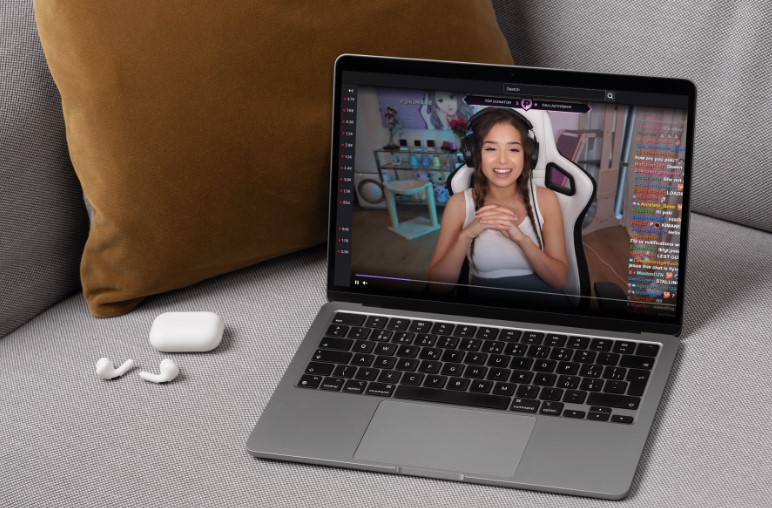 A laptop displays a live stream, featuring Pokimane
