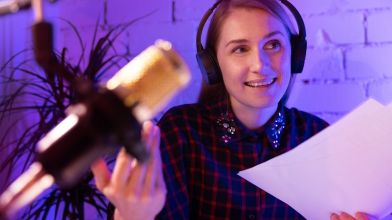 A woman recording a podcast with headphones and a microphone, sharing tips on money and lifestyle
