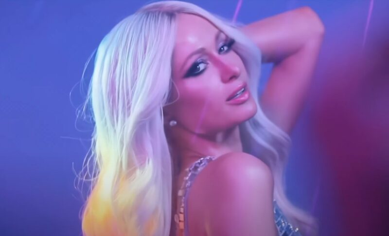 Paris Hilton, radiating confidence and style in a vibrant, colorful studio portrait
