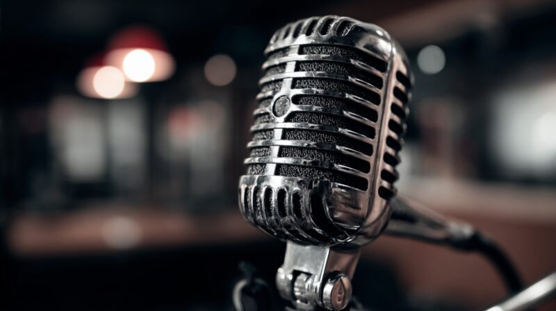 Close-up of a vintage-style microphone in a dimly lit podcast studio