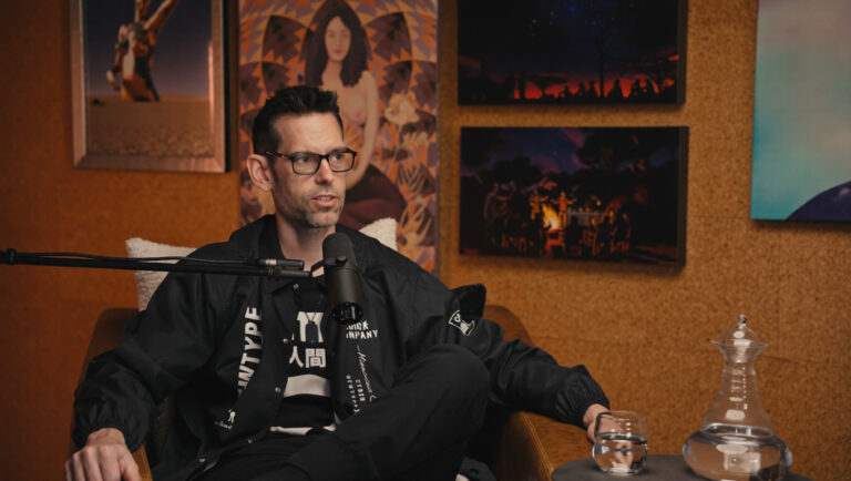 Man wearing glasses speaking into a microphone in a studio setting